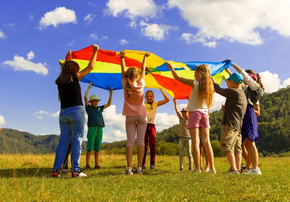 Children holding a rainbow parachute outdoors